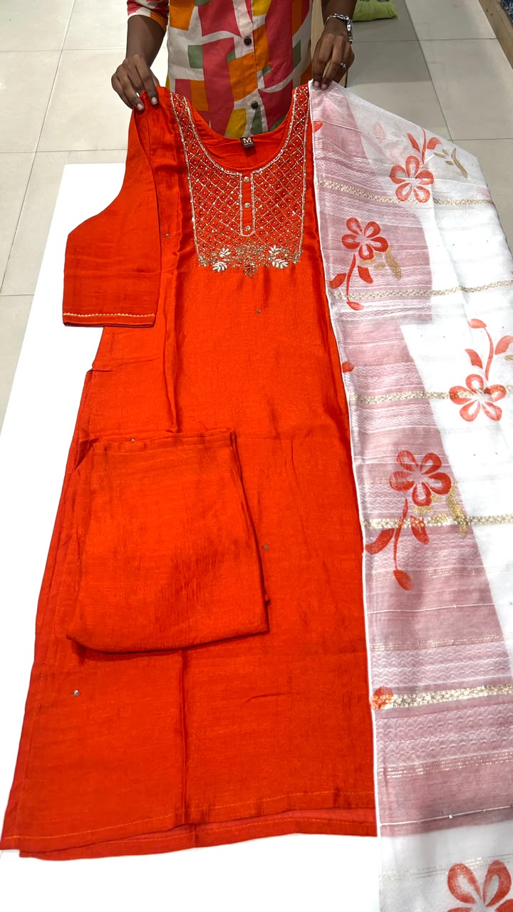Red traditional outfit with white dupatta featuring floral patterns on a tiled floor.